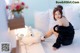 A woman sitting on the floor next to a white teddy bear.