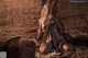 A naked woman sitting on a pile of hay.