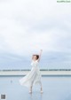 A woman in a white dress standing on top of a roof.