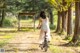 A woman in a white dress riding a bike down a dirt road.