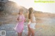 A couple of women standing next to each other on a beach.