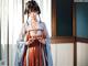 A woman in a kimono standing in front of a window.