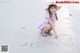 A woman sitting on the beach writing a heart in the sand.