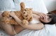 A woman laying on a bed holding a teddy bear.