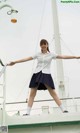 A woman in a white shirt and blue skirt standing on a boat.