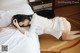 A woman laying on a bed in a white shirt.