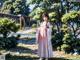 A woman in a pink and white kimono standing in a park.