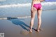 A woman in a pink bikini standing on a beach.