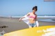 A woman in a pink bikini standing next to a yellow surfboard.