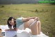 A woman in a white bikini laying on a blanket in a field.