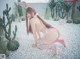 A woman in a pink bunny costume crouching on a bed of white pebbles.