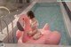 A woman sitting on an inflatable flamingo in a swimming pool.